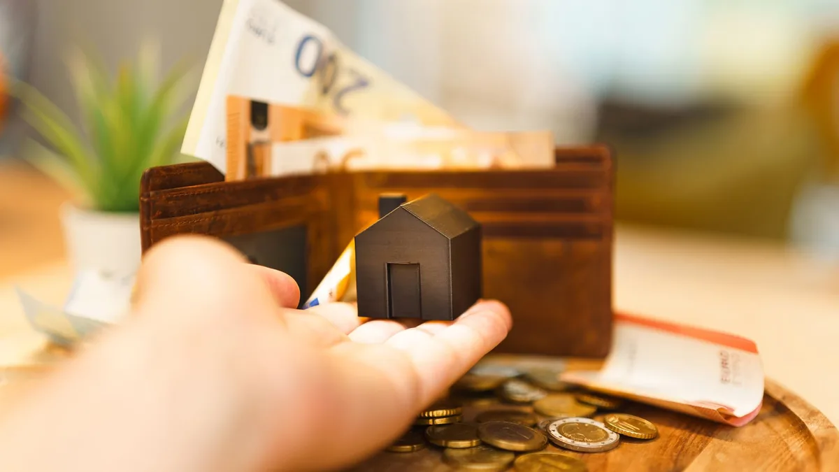 Banconote in euro, monete e un piccolo modello di casa: i costi annuali di una seconda casa