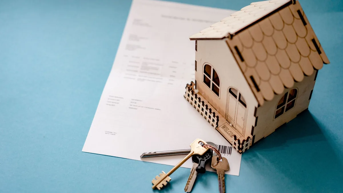Modello di casa in legno, chiavi e contratto: vendere o affittare la seconda casa